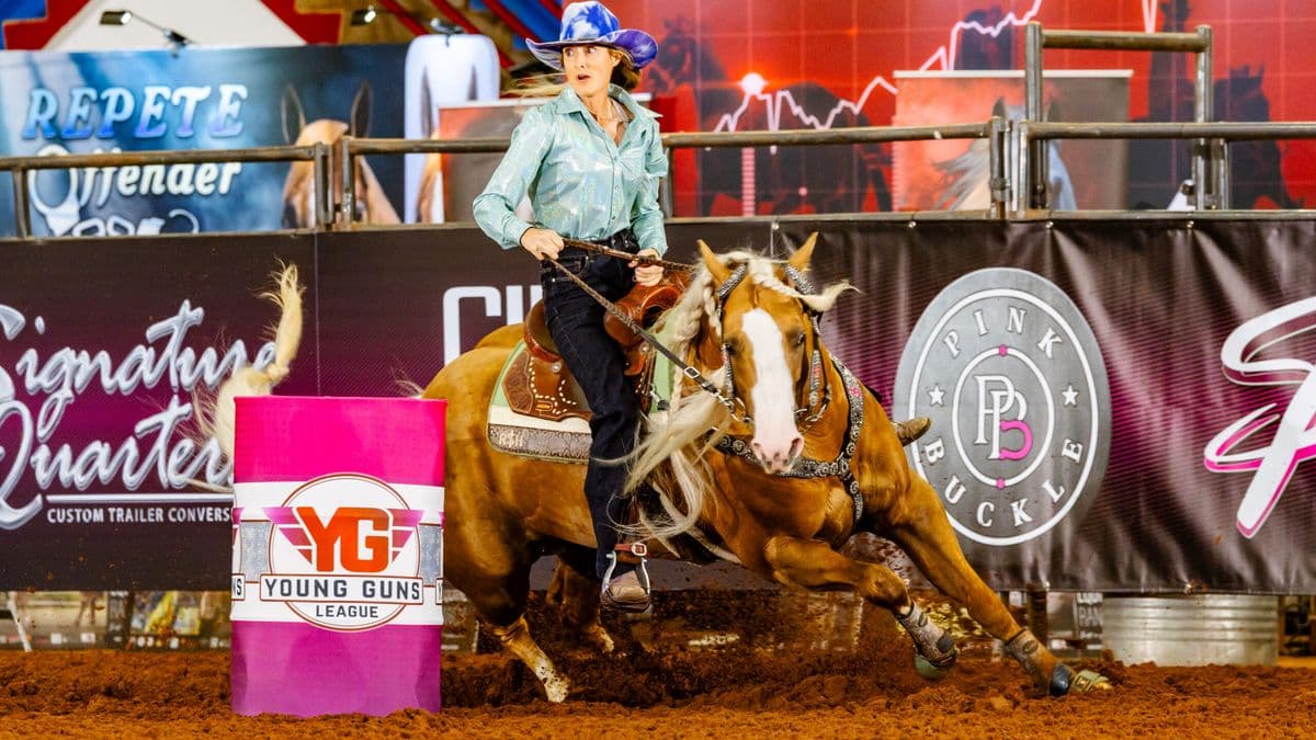 Tricia Aldridge turns a barrel in a purple hat on her yellow horse