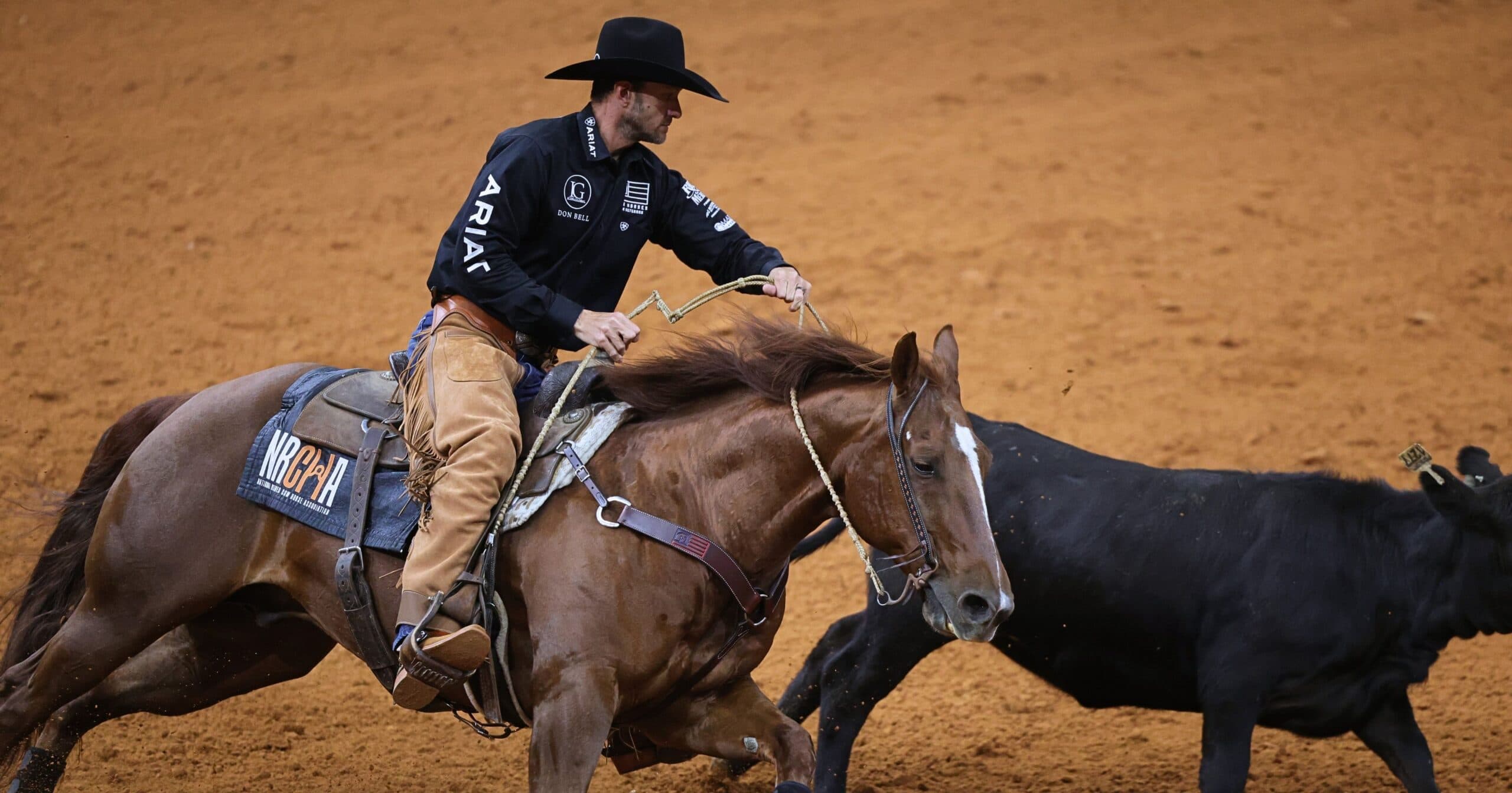 Rodeo competitor on horseback roping a steer during a ranch sorting event on a dirt arena