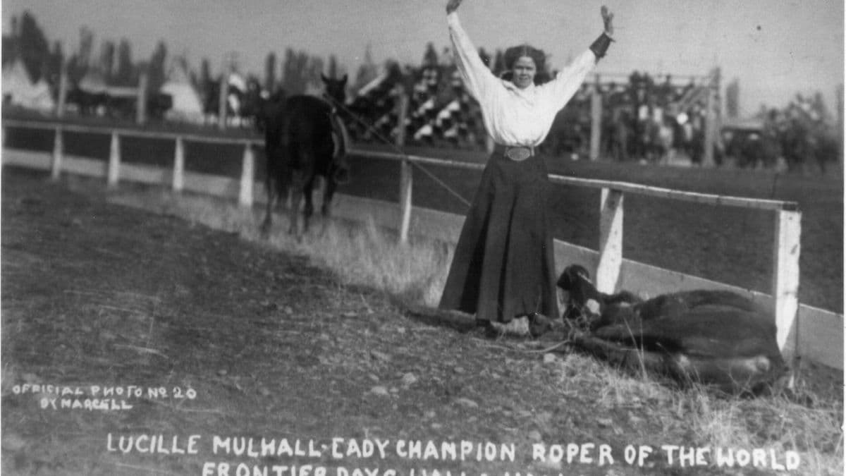 Lucille Mulhall, champion roper, celebrates with arms raised while mounted on horse at 1914 Frontier Days in Walla Walla, Washington