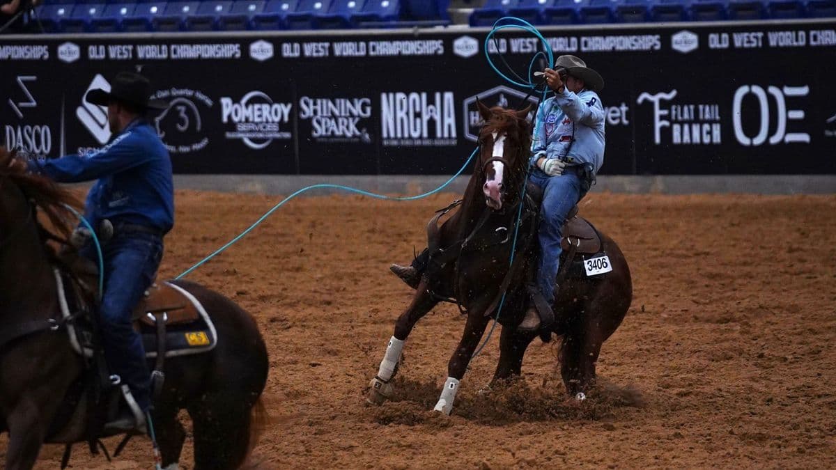 Hunter Koch swings his rope on Rebel X, a sorrel stallion with a blaze, in front of Old West World Championships banners in Amarillo.