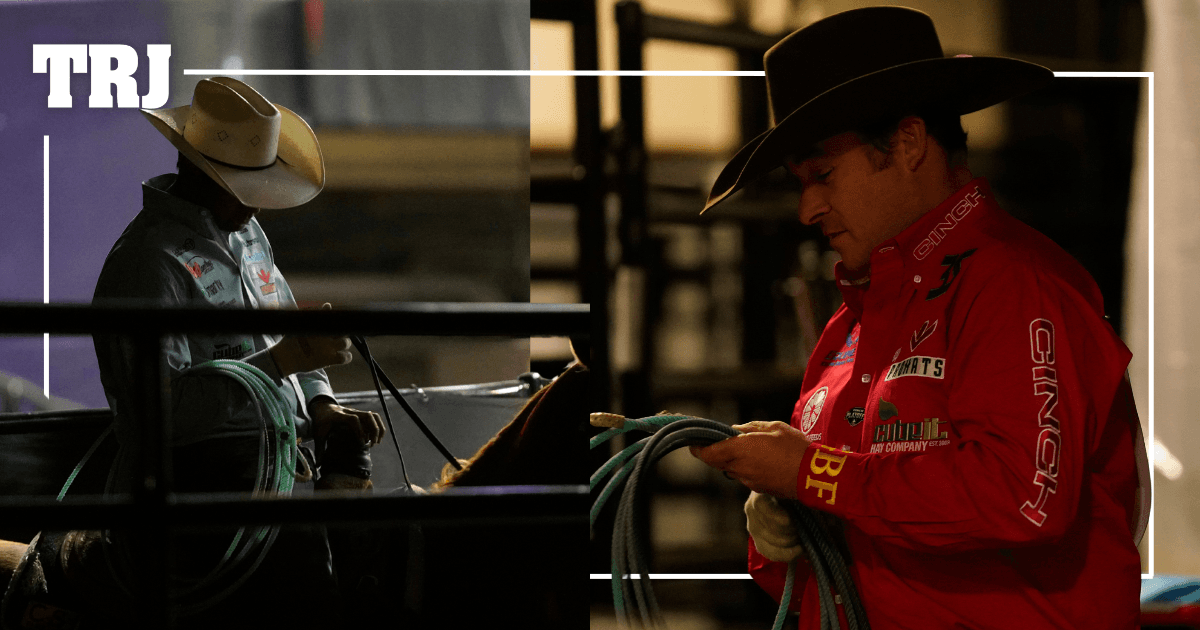 Two rodeo cowboys in cowboy hats hold coiled ropes while standing at a fence rail during a competition