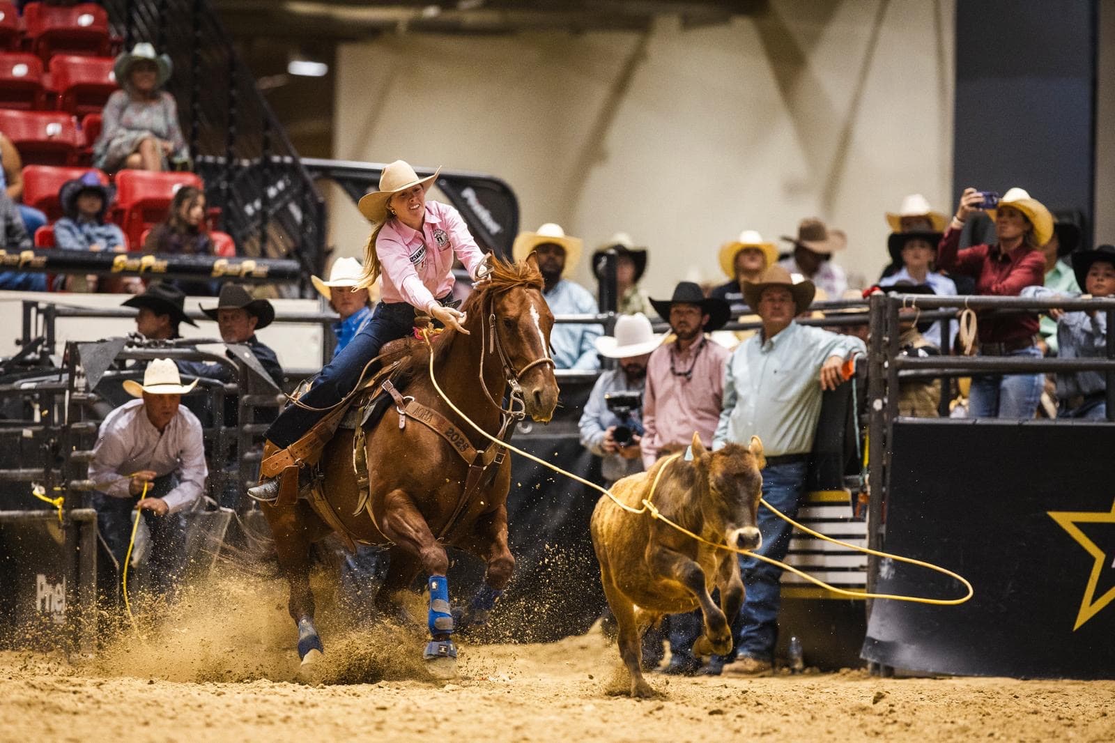 Hadley Thompson ropes a calf in a pink shirt