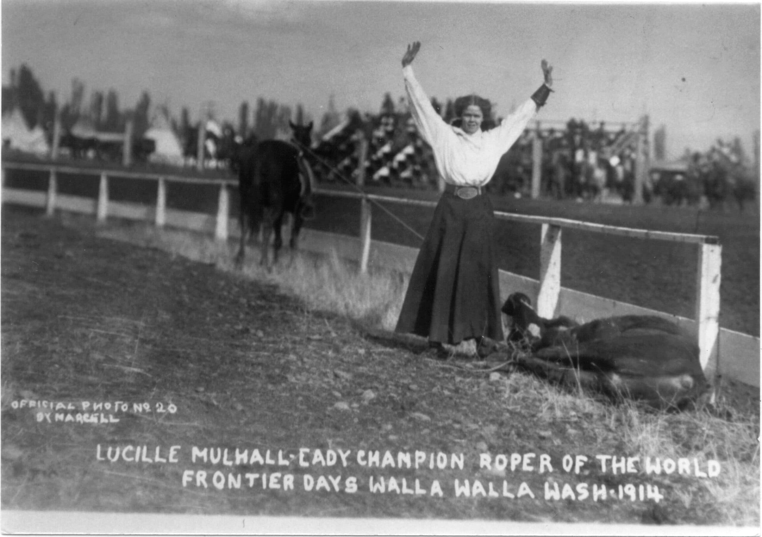 Lucille Mulhall, champion roper, celebrates with arms raised while mounted on horse at 1914 Frontier Days in Walla Walla, Washington
