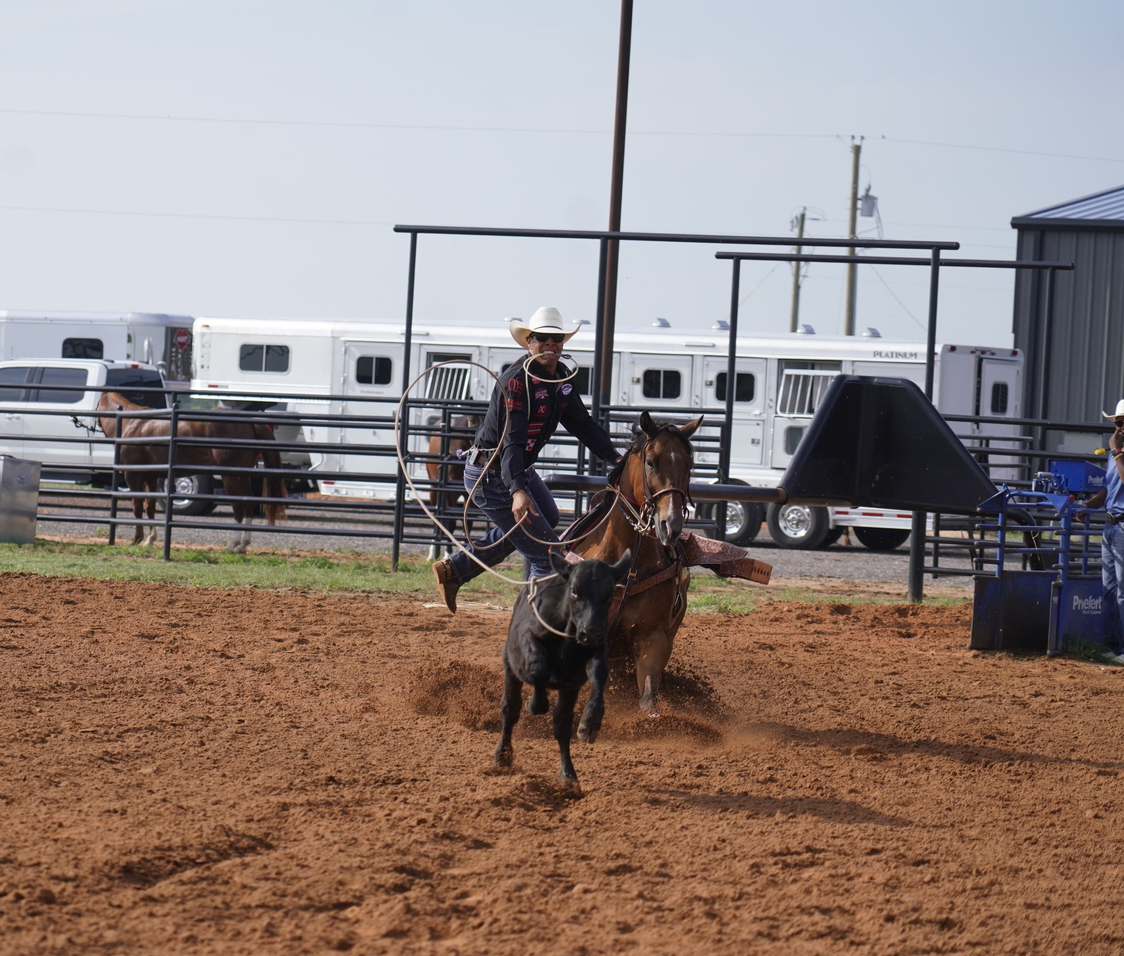 Shad Mayfield getting off his horse to tie a calf.