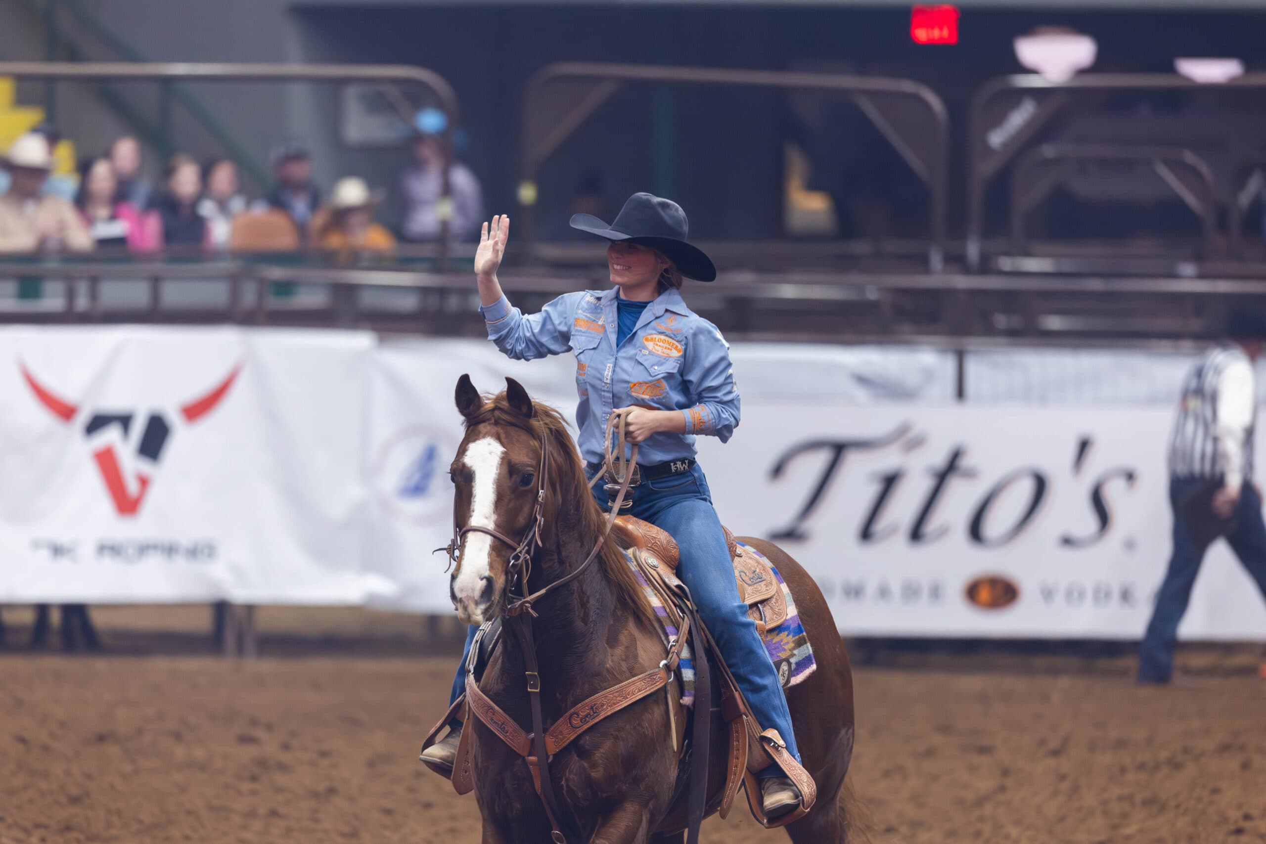 Hali Williams waving to the crowd after roping a calff in roudn 1 of the 2025 nfbr in Fort Worth, TX